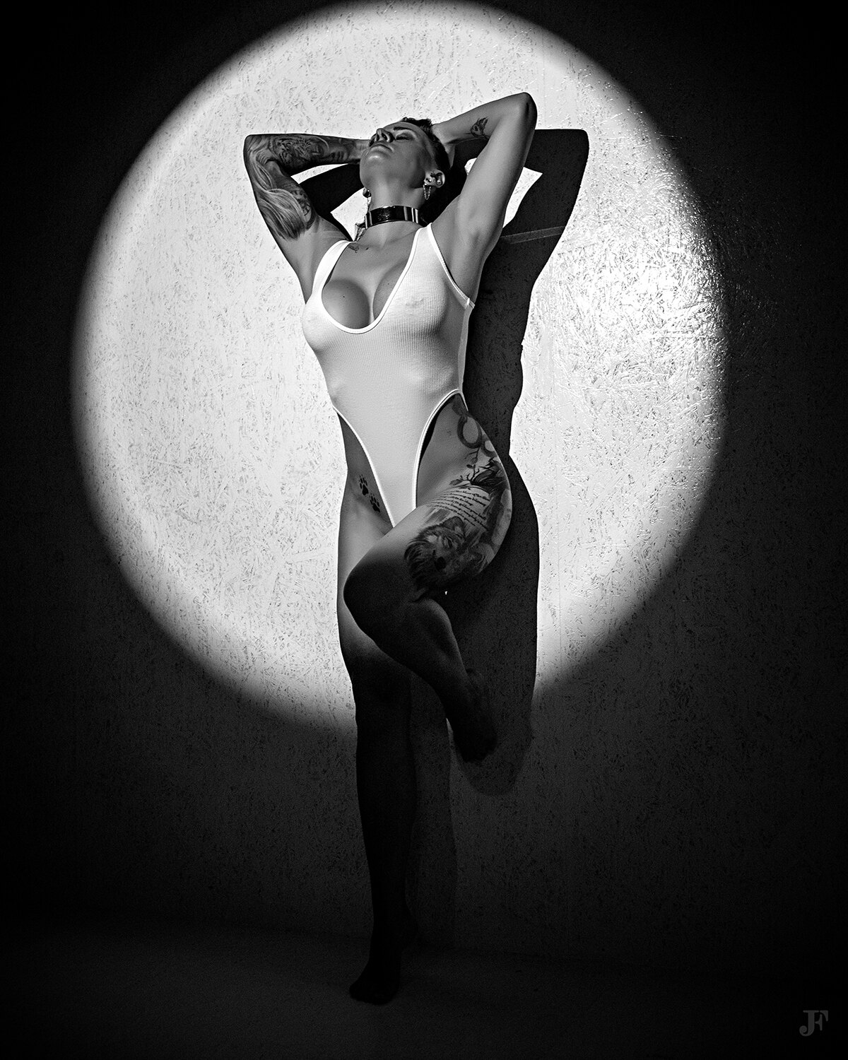 The image shows a woman in a white bodysuit leaning against a wall with her arms outstretched, illuminated by a full moon in the background.