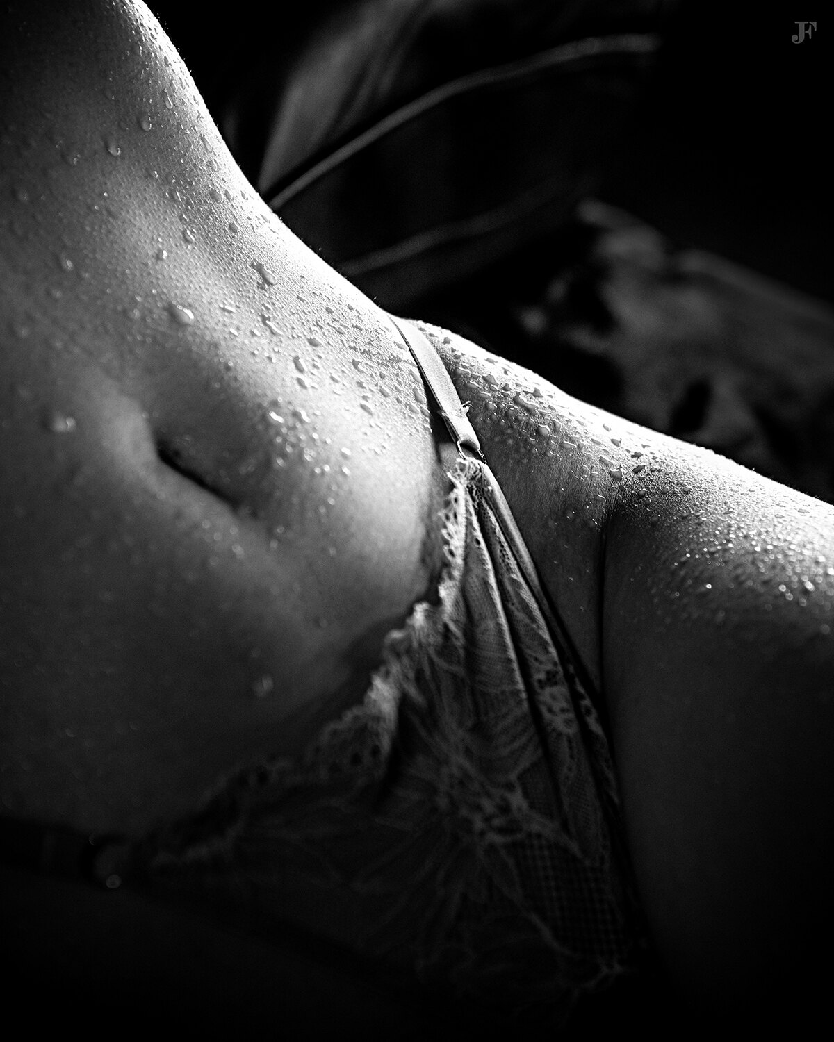 The image shows a black and white photo of a woman in a bikini with water droplets on her body. The background is dark and there is a watermark in the top right corner.