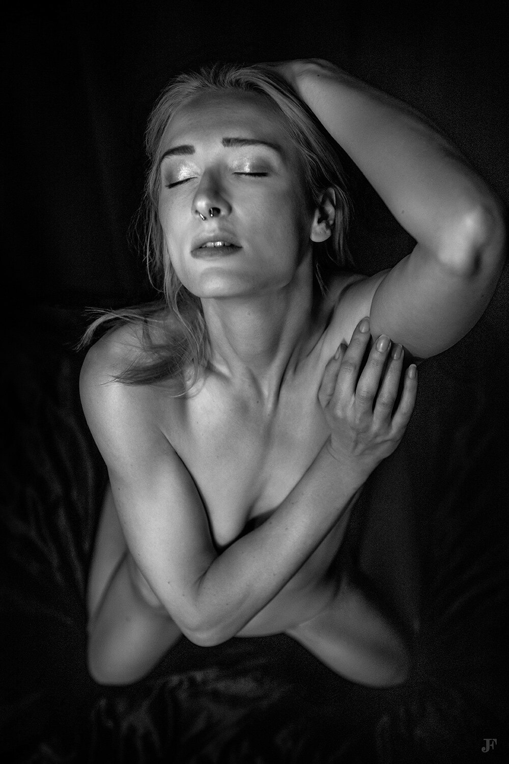 In this image we can see a woman is sitting on a cloth. The background of the image is dark.